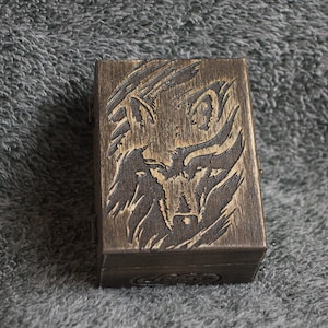 May include: A wooden box with a carved wolf design. The box is dark brown and has a hinged lid.