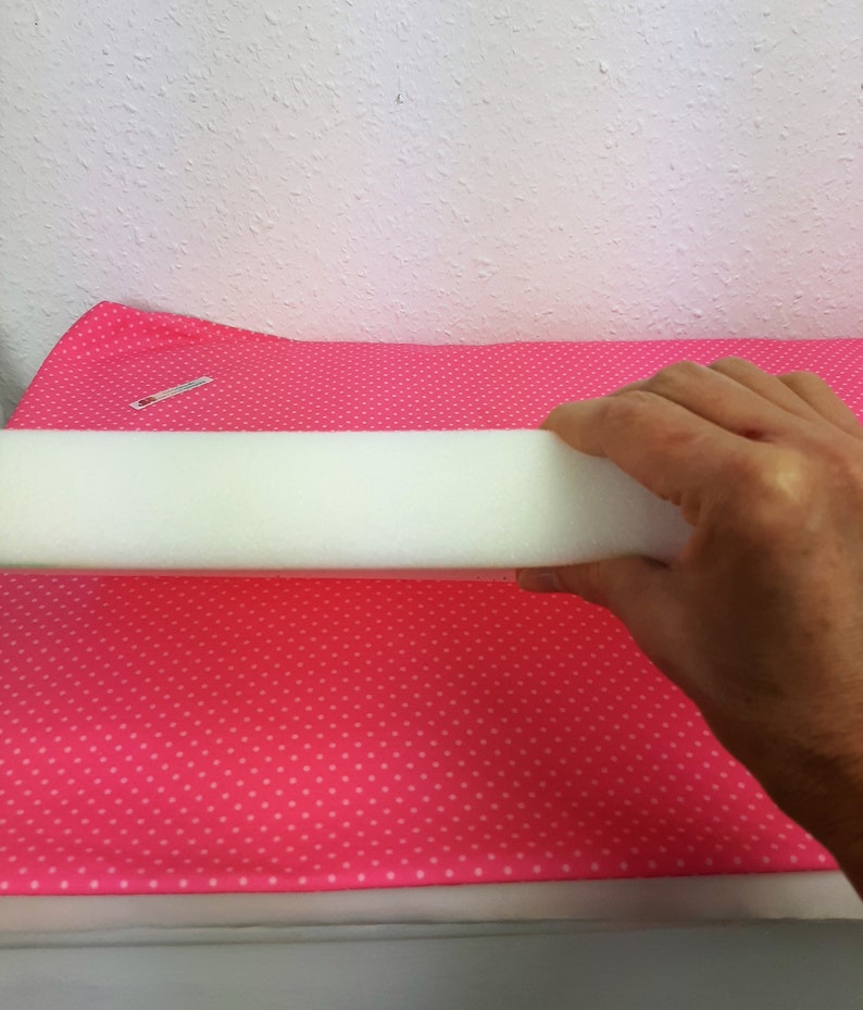 May include: A white foam pipe insulation tube on a pink fabric with white polka dots.