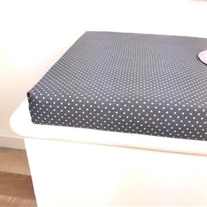 May include: A gray and white polka dot cushion top for a storage bench.