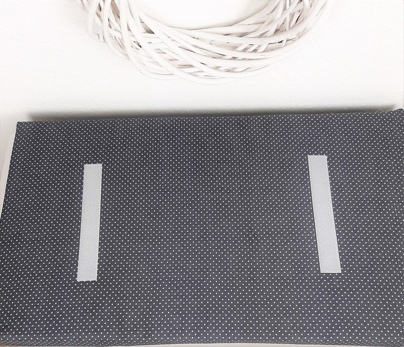 May include: A dark gray fabric with white polka dots. Two white strips of tape are attached to the fabric, one on each side.