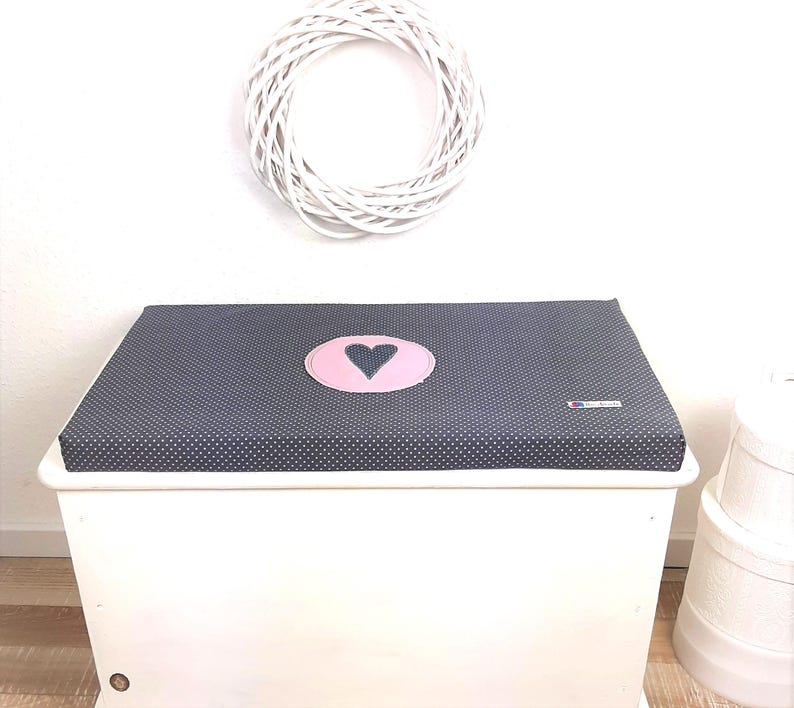 May include: A white toy chest with a dark blue and white polka dot lid. The lid has a pink circle with a dark blue heart in the center.