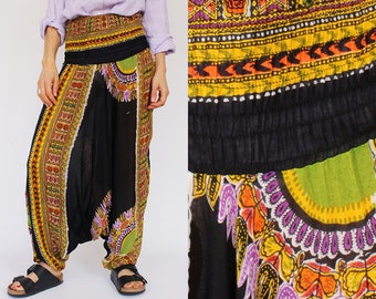 Puede incluir: Pantalones harem negros con una cintura ancha estampada y paneles decorativos. Los paneles presentan un diseño colorido con detalles en amarillo, naranja, morado y verde. Los pantalones tienen un ajuste holgado y fluido y están hechos de tela ligera.