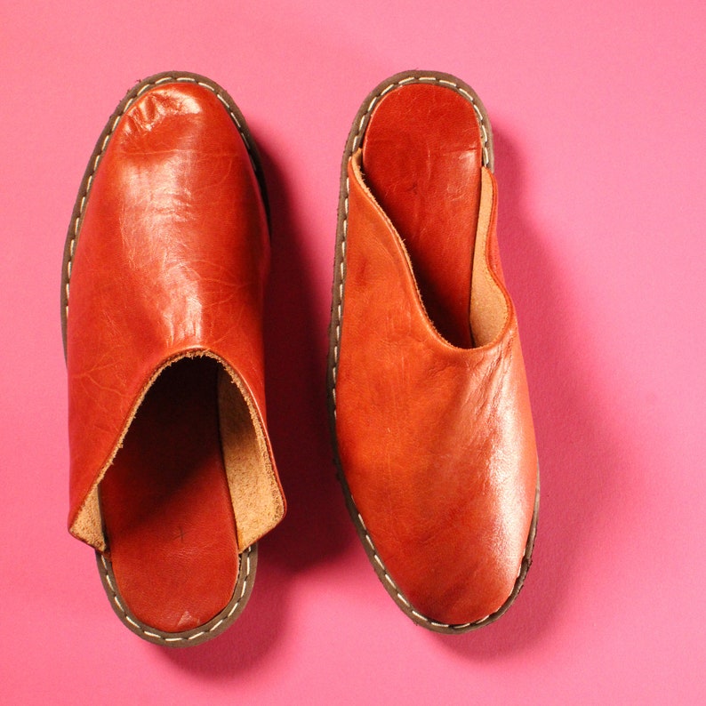Op de afbeelding: Vintage 1970s Handgemaakte Deadstock Indiase loafers muiltjes instappers. Twee paar bruine leren slippers met een ronde neus en een open achterkant. De slippers hebben een eenvoudig ontwerp en zijn gemaakt van stevig leer.
