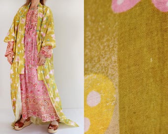 May include: A long yellow and pink floral print kimono with a pink floral print dress underneath. The kimono has a wide, flowing silhouette and is made of a lightweight fabric.
