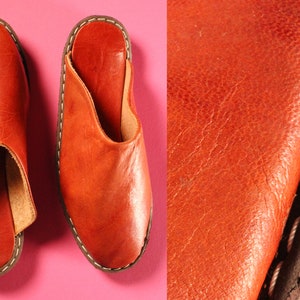 Op de afbeelding: Vintage 1970s Handgemaakte Deadstock Indiase loafers muiltjes instappers. Een paar bruine leren slippers met een gestikte rand. De slippers hebben een ronde neus en een open achterkant.