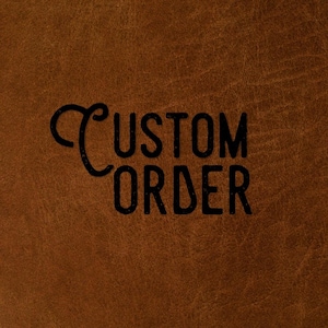 May include: A brown leather surface with a visible grain texture featuring the black text CUSTOM ORDER printed in the centre. The word CUSTOM is written in a stylised font with a decorative C, while ORDER is in a bold sans-serif font.