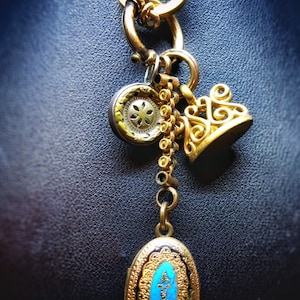 Colección antigua de colgantes victorianos que consta de un medallón esmaltado bañado en oro, un dije monograma bañado en oro y un dije de plata esterlina.
