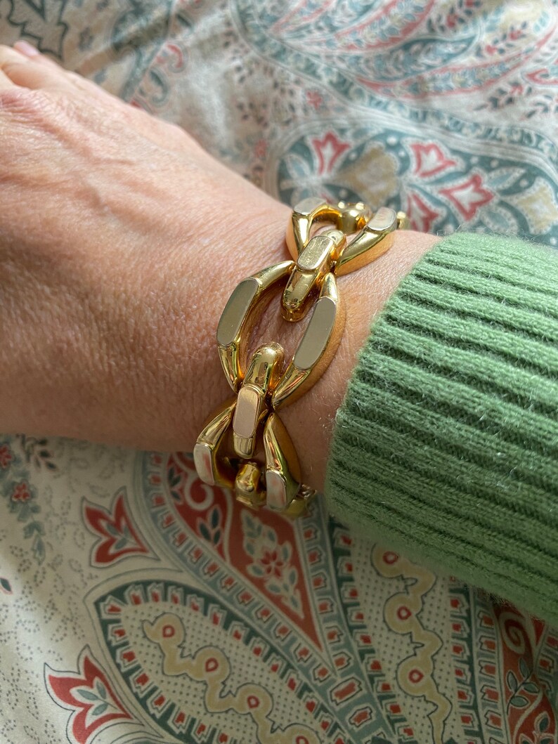 K&ouml;nnte beinhalten: Ein goldfarbenes Gliederarmband mit einem klobigen Design. Das Armband ist aus Metall und hat eine polierte Oberfl&auml;che.