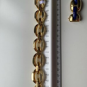 K&ouml;nnte beinhalten: Ein goldenes Kettenarmband mit einem Verschluss. Das Armband besteht aus ineinandergreifenden ovalen Gliedern. Das Armband wird an einem Lineal gemessen.