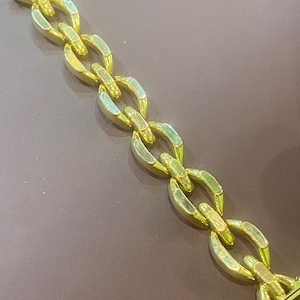 K&ouml;nnte beinhalten: Ein goldenes Kettenarmband mit einem einzigartigen Gliederdesign. Die Glieder sind oval geformt und haben eine strukturierte Oberfl&auml;che.