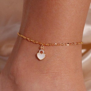 May include: Gold ankle chain with a white heart charm.