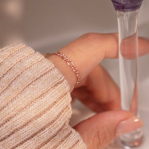 May include: A delicate rose gold chain bracelet with a simple, classic design. The bracelet is shown on a person's wrist.