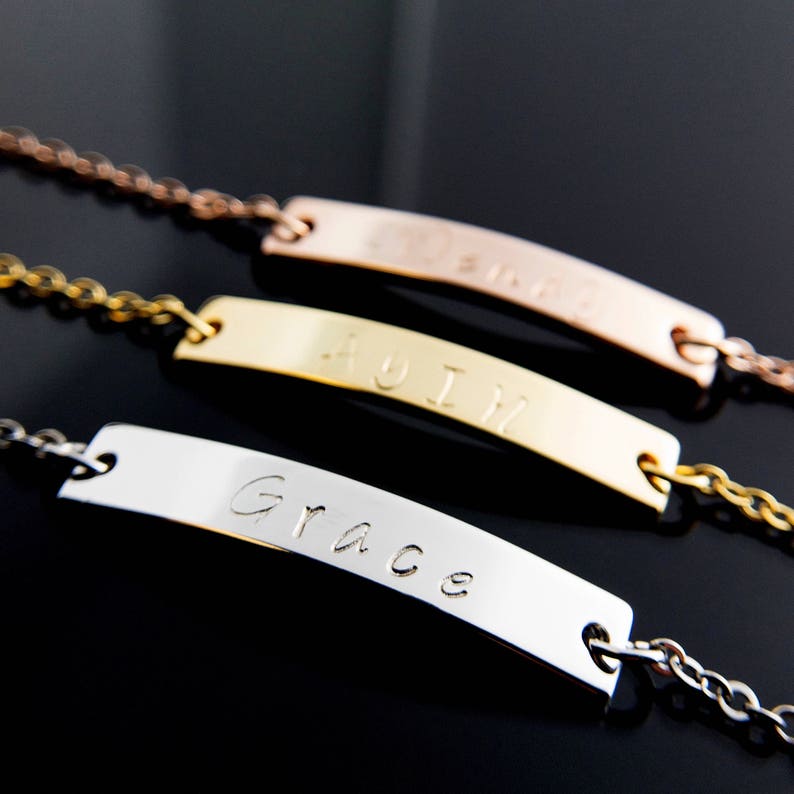 May include: Three gold bar necklaces with the names "Grace", "Mom", and "Emily" engraved on them.