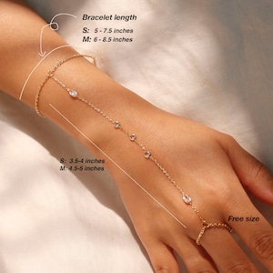 May include: A gold chain bracelet with clear stones. The bracelet is adjustable and can be worn as a finger ring or a bracelet. The bracelet is available in two sizes: S (3.5-4 inches) and M (4.5-5 inches). The bracelet length is also adjustable: S (5-7.5 inches) and M (6-8.5 inches).