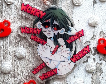 May include: A clear acrylic keychain featuring a cartoon character with green hair and red eyes. The character is holding their arms around their body and has stitches on their arms. The keychain has the word "worry" written around the edge in red.