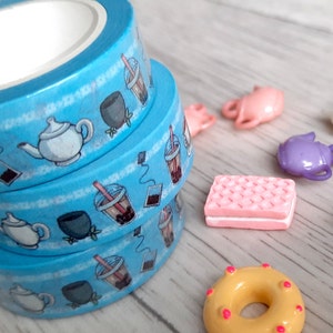 Pode incluir: Tr&ecirc;s rolos de fita washi azul com um tema de ch&aacute; e boba. A fita apresenta ilustra&ccedil;&otilde;es de bules, x&iacute;caras de ch&aacute;, ch&aacute; boba e saquinhos de ch&aacute;.