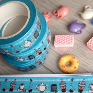 Pode incluir: Tr&ecirc;s rolos de fita washi azul com um tema de ch&aacute; e boba. A fita apresenta ilustra&ccedil;&otilde;es de x&iacute;caras de ch&aacute;, bules, ch&aacute; boba e saquinhos de ch&aacute;.