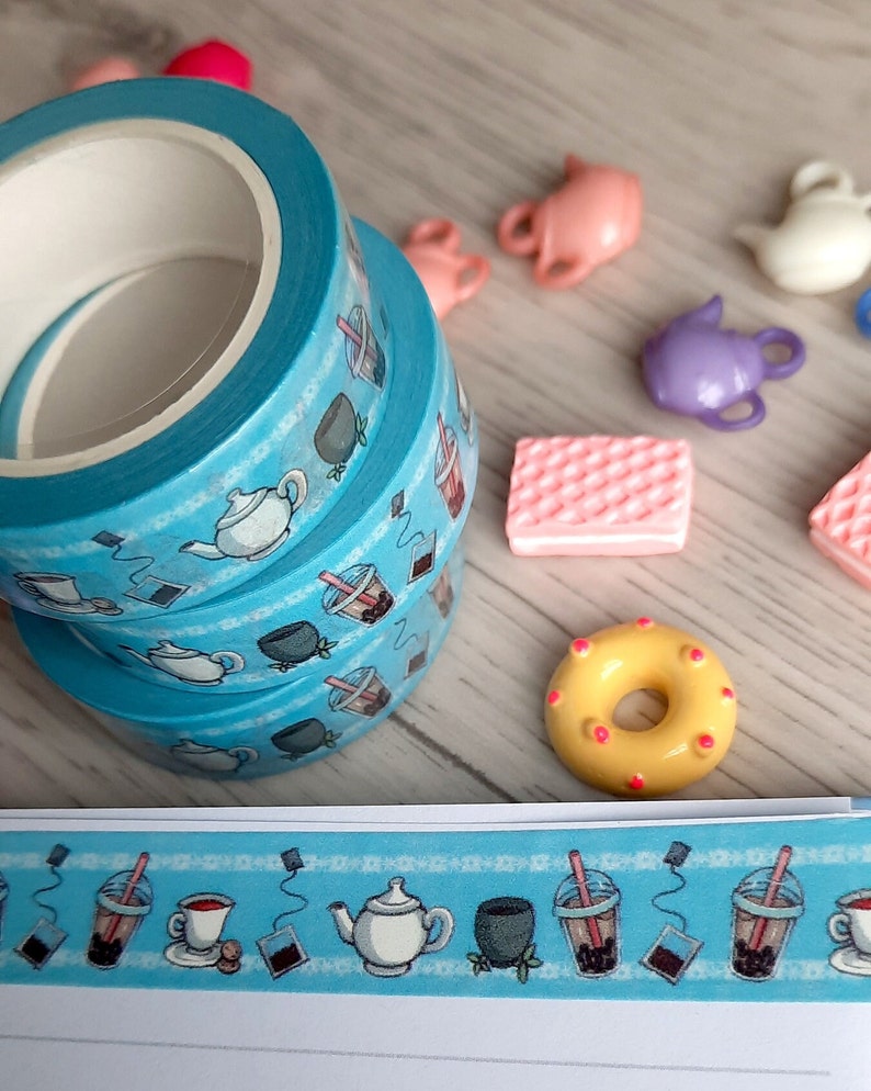 Pode incluir: Tr&ecirc;s rolos de fita washi azul com um tema de ch&aacute; e boba. A fita apresenta ilustra&ccedil;&otilde;es de x&iacute;caras de ch&aacute;, bules, ch&aacute; boba e saquinhos de ch&aacute;.