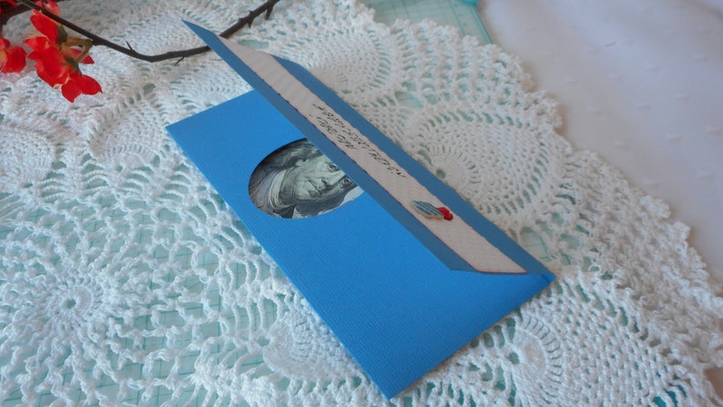 May include: A blue card with a cut-out window revealing a dollar bill. The card has a message that reads "You are worth more than you think."