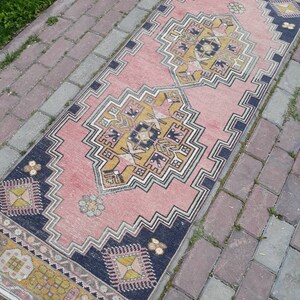 May include: A pink and navy blue runner rug with a geometric pattern. The rug has a traditional design with intricate details.