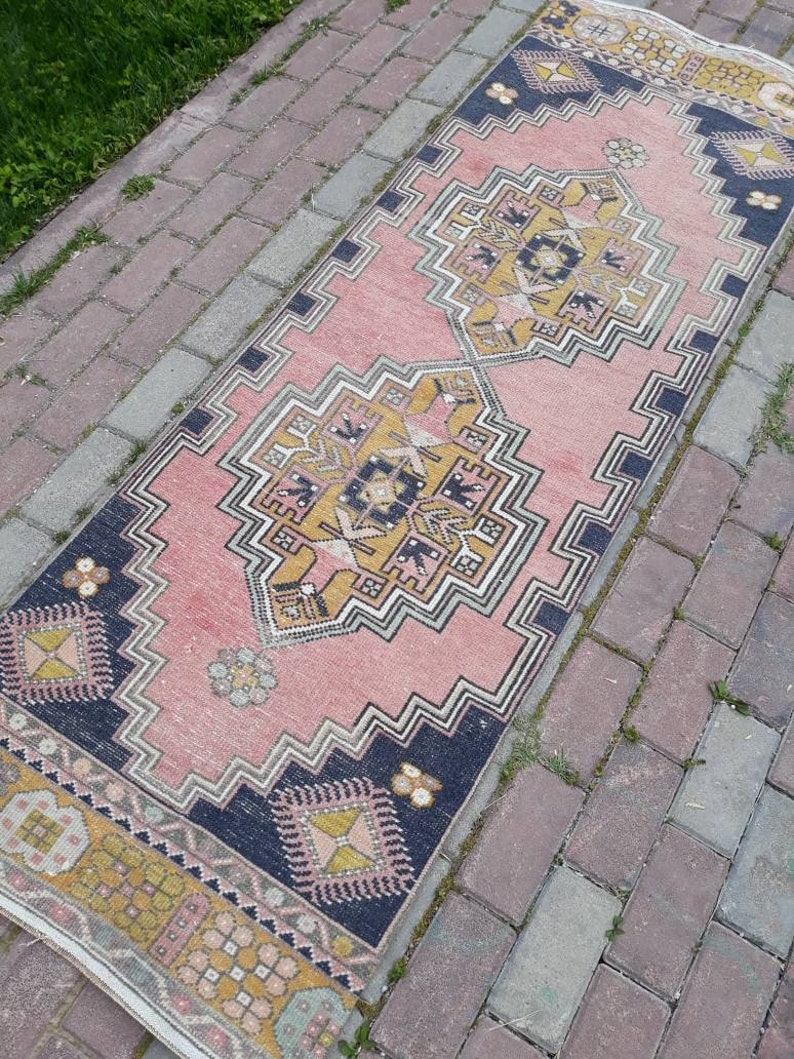 May include: A pink and navy blue runner rug with a geometric pattern. The rug has a traditional design with intricate details.