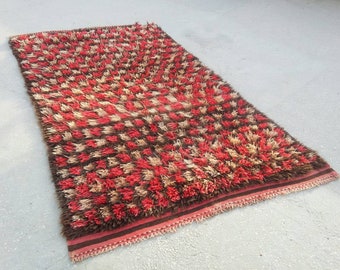 May include: A red, brown, and cream colored shag rug with a checkered pattern. The rug has a fringe border.