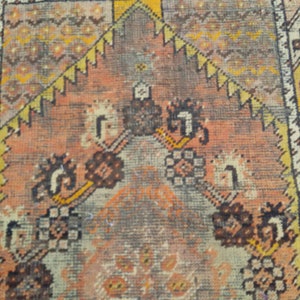 May include: Close-up of a vintage rug with a repeating pattern of geometric shapes and floral motifs in shades of brown, orange, and beige.