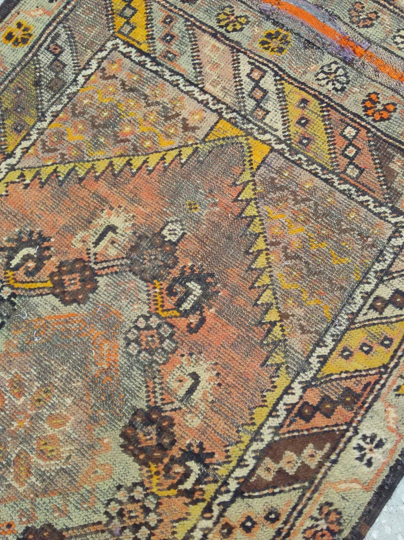 May include: A vintage rug with a geometric pattern in shades of brown, orange, yellow, and white. The rug has a faded, distressed look, giving it a unique character.