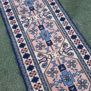 May include: A pink and blue patterned rug with a geometric design. The rug has a white background with pink and blue floral motifs.