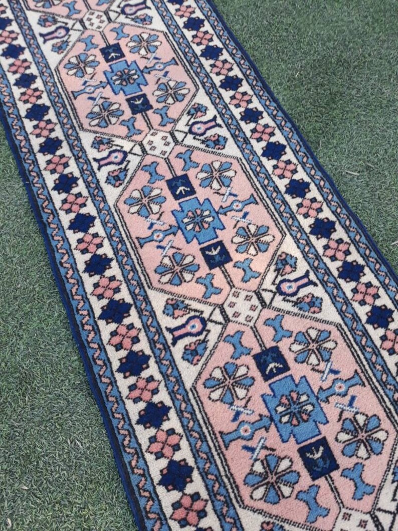 May include: A pink and blue patterned rug with a geometric design. The rug has a white background with pink and blue floral motifs.