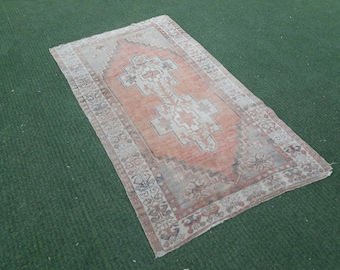 Puede incluir: Una alfombra turca vintage con un esquema de color naranja y crema descolorido. La alfombra tiene un patrón geométrico tradicional con un medallón central. La alfombra está en buen estado con algo de desgaste.