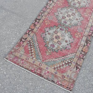 May include: A vintage pink and cream runner rug with a traditional floral pattern. The rug has a faded, distressed look and is perfect for adding a touch of bohemian style to your home.