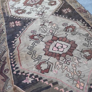 May include: A vintage rug with a geometric pattern in shades of brown, pink, and white. The rug has a worn and faded look, giving it a rustic and antique feel.