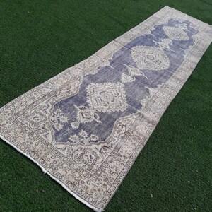 May include: A long, rectangular rug with a cream and blue patterned design. The rug has a faded, vintage look and is perfect for adding a touch of bohemian style to any room.