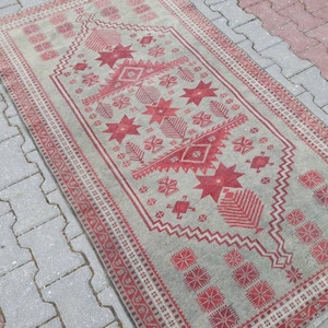 Könnte beinhalten: Ein Vintage-Teppich mit einem geometrischen Muster in Rot- und Grüntönen. Der Teppich hat einen verblassten Look und ist aus Wolle.