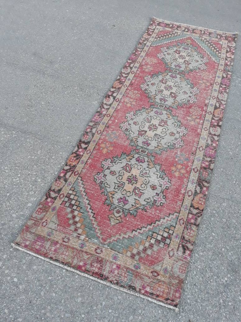 May include: A vintage pink and cream runner rug with a traditional floral pattern. The rug has a faded, distressed look and is approximately 2 feet wide and 6 feet long.