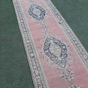 May include: A pink runner rug with a floral pattern and intricate border. The rug has a traditional design with a central medallion and repeating motifs.