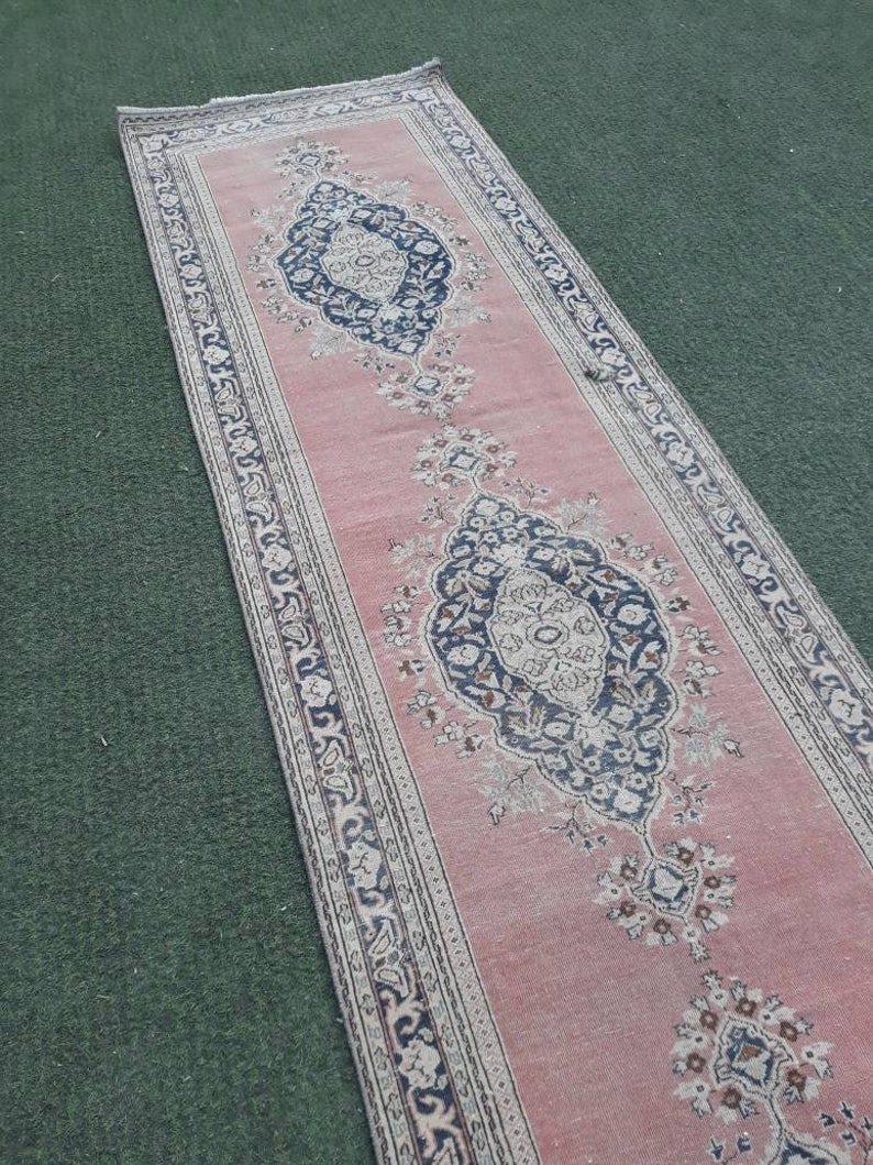May include: A pink runner rug with a floral pattern and intricate border. The rug has a traditional design with a central medallion and repeating motifs.