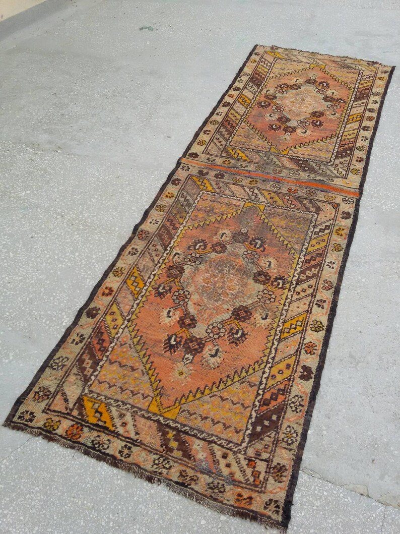 May include: A long, narrow rug with a traditional Persian design. The rug is made of wool and has a brown, orange, and cream color scheme. The rug has a fringe on both ends.