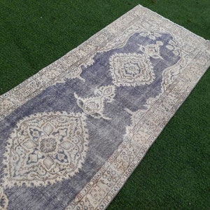 May include: A vintage style runner rug with a blue background and a white and beige floral pattern. The rug has a distressed look and is perfect for adding a touch of bohemian style to your home.