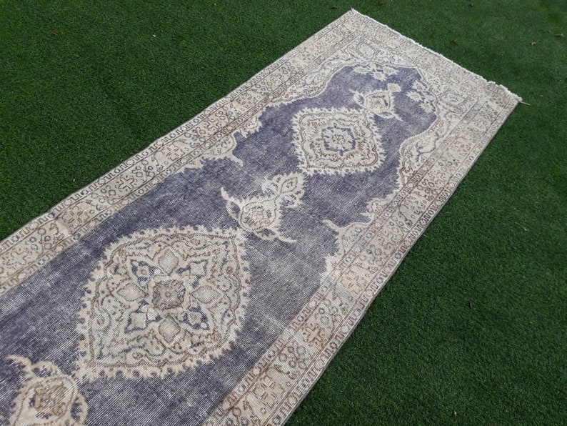 May include: A vintage style runner rug with a blue background and a white and beige floral pattern. The rug has a distressed look and is perfect for adding a touch of bohemian style to your home.