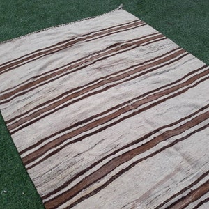 May include: A white and brown striped rug with a woven texture. The rug has a simple design with horizontal stripes.