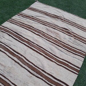 May include: A white and brown striped rug with a woven texture. The rug has a subtle sheen and is made of natural fibres.