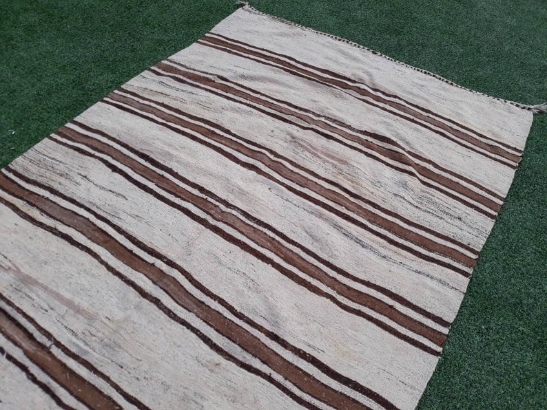 May include: A white and brown striped rug with a woven texture. The rug has a subtle sheen and is made of natural fibres.