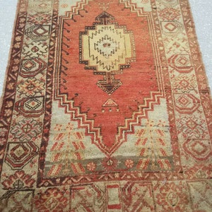 May include: A vintage Turkish rug with a red, cream, and brown color scheme. The rug has a central medallion with intricate geometric patterns and a border with floral motifs.