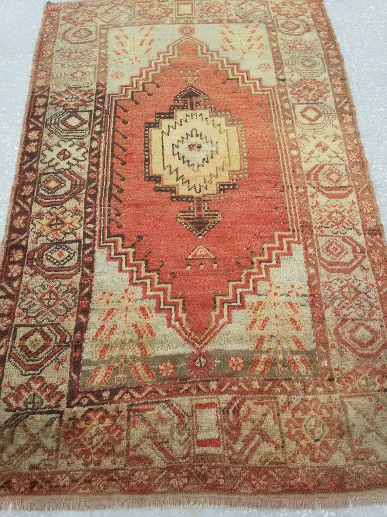 May include: A vintage Turkish rug with a red, cream, and brown color scheme. The rug has a central medallion with intricate geometric patterns and a border with floral motifs.