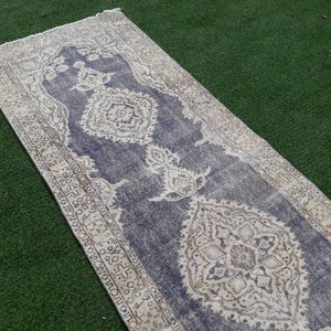 May include: A vintage runner rug with a faded blue background and intricate white floral patterns. The rug has a distressed look and is perfect for adding a touch of bohemian style to any room.