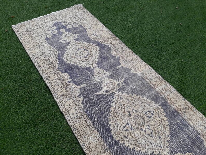 May include: A vintage runner rug with a faded blue background and intricate white floral patterns. The rug has a distressed look and is perfect for adding a touch of bohemian style to any room.