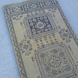 May include: A beige and brown patterned rug with a geometric design. The rug has a fringed edge and is made of a woven material.