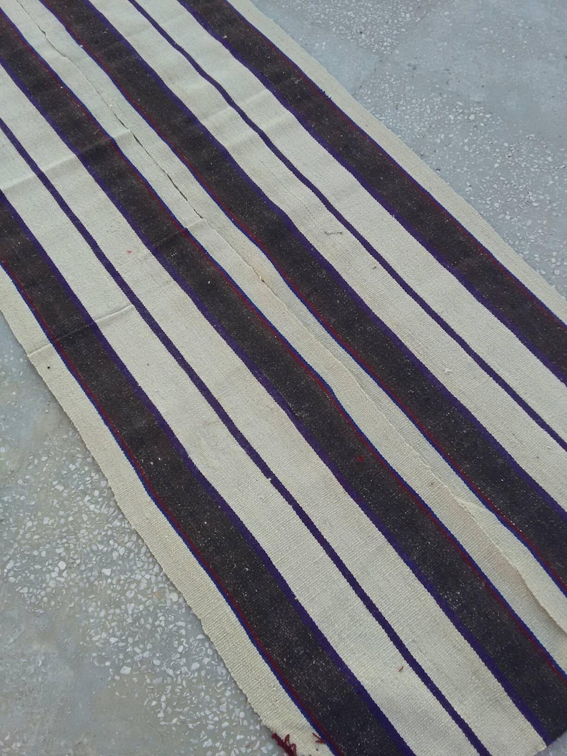 May include: A white and black striped rug with a red accent. The rug is woven with thick, textured yarn.